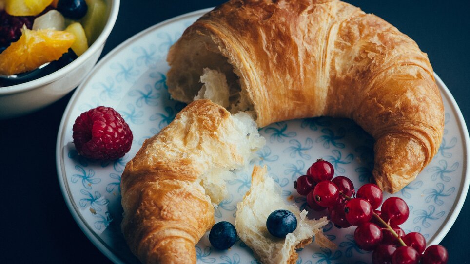Un croissant fresco su un piatto con bacche e insalata di frutta. | © Promenade - Joel Kernasenko