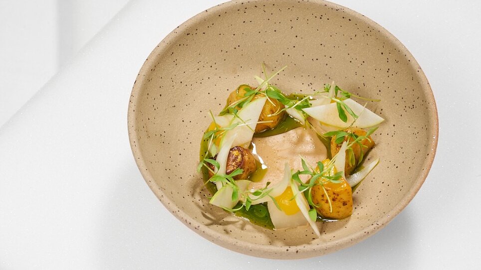 Plate with a creative dish, garnished with fresh herbs. | © Artis