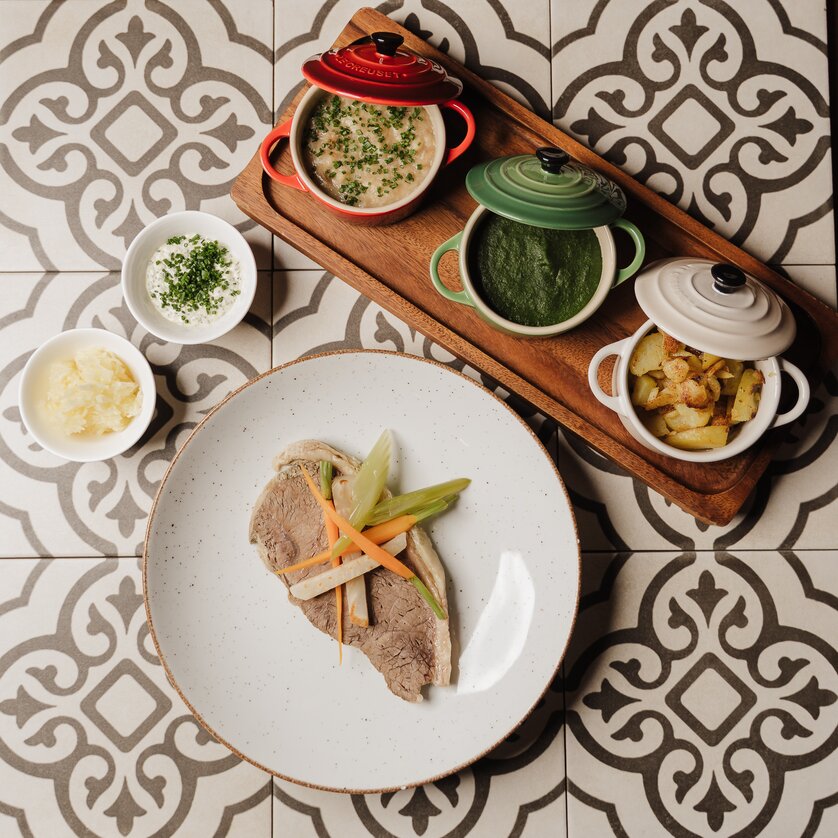 Un piatto con carne e verdure, accompagnato da vari contorni in pentole. | © Restaurant Florian