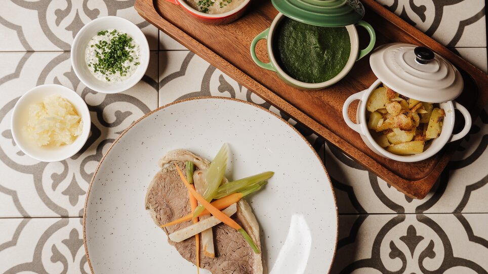 A plate with meat and vegetables, accompanied by various side dishes in pots. | © Restaurant Florian