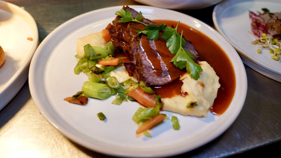 A plate with beef, vegetables, and mashed potatoes, garnished with parsley. | © Wirtshaus Schanzlwirt