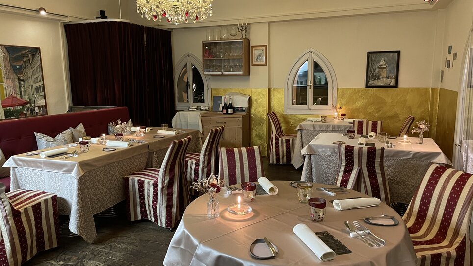 Elegant restaurant view with tables and chairs, candlelight, and a chandelier. | © Starcke Haus