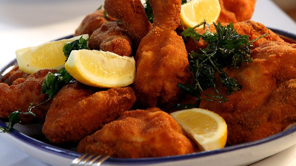 Fried chicken pieces served with lemon slices and herbs. | © Stoffbauer