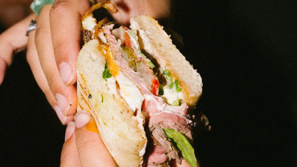 Una persona tiene un panino con vari ingredienti. | © Bobby's Agency - Simon Bauer