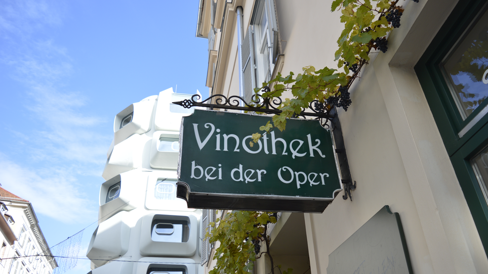 Ein Schild der Vinothek bei der Oper in Graz, umgeben von Weinreben. | © Vinothek bei der Oper