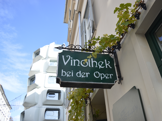 Ein Schild der Vinothek bei der Oper in Graz, umgeben von Weinreben. | © Vinothek bei der Oper