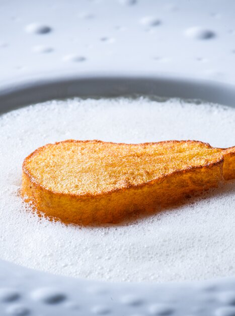 Ein kunstvoll angerichtetes Gericht mit einem knusprigen Stück und Schaum. | © Jürgen Schmücking