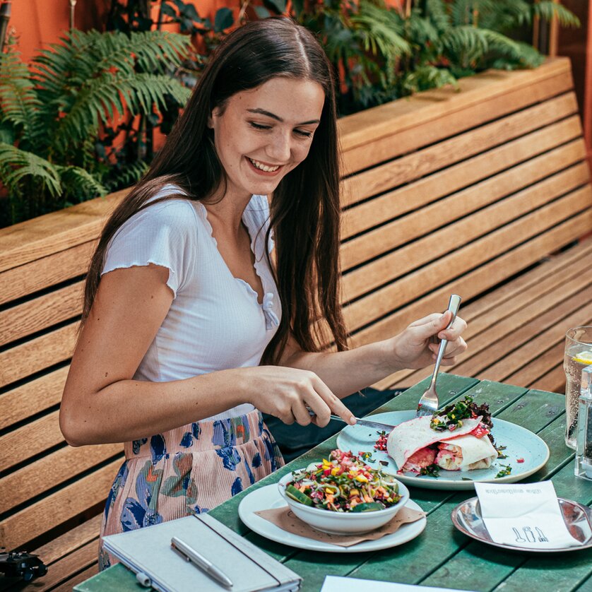 GenussHauptstadt Graz | © Graz Tourismus Junge Frau genießt eine Mahlzeit in einem Außenbereich in Graz. | © Graz Tourismus