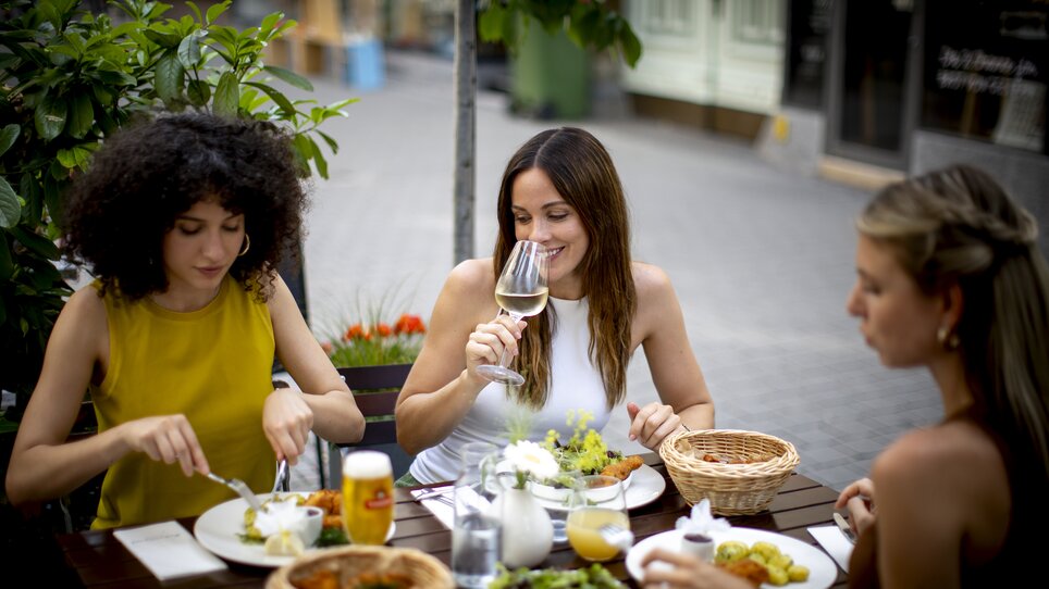 Drei Frauen genießen ein gutes Essen und Getränke im Freien. | © Graz Tourismus - Tom Lamm