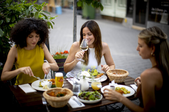 Three women enjoying a meal and drinks outdoors. | © Graz Tourismus - Tom Lamm