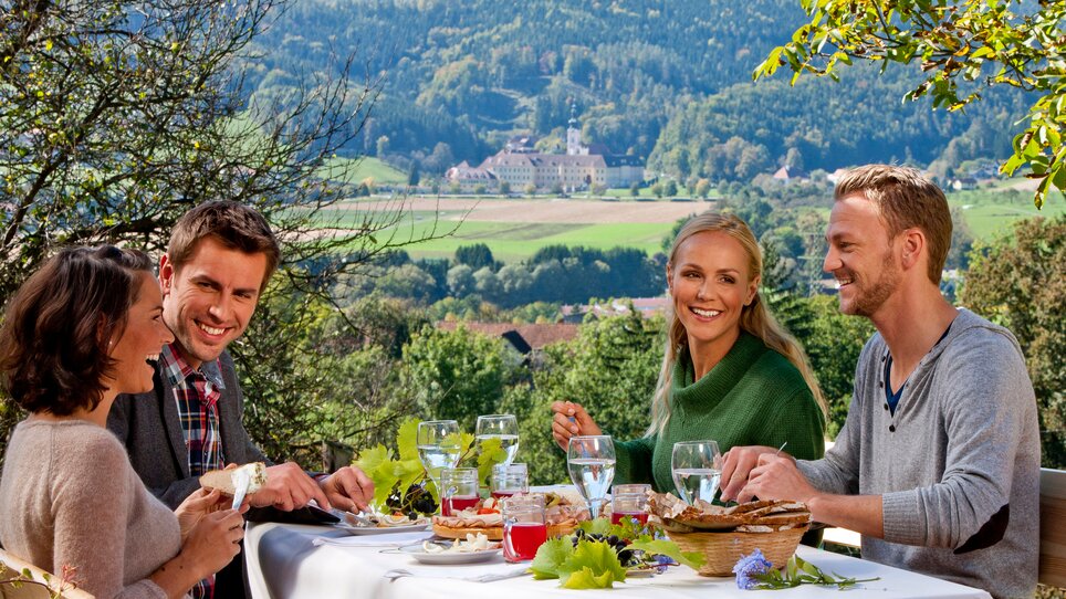 Freunde genießen ein festliches Essen in der Natur mit Blick auf die Landschaft. | © Tom Lamm