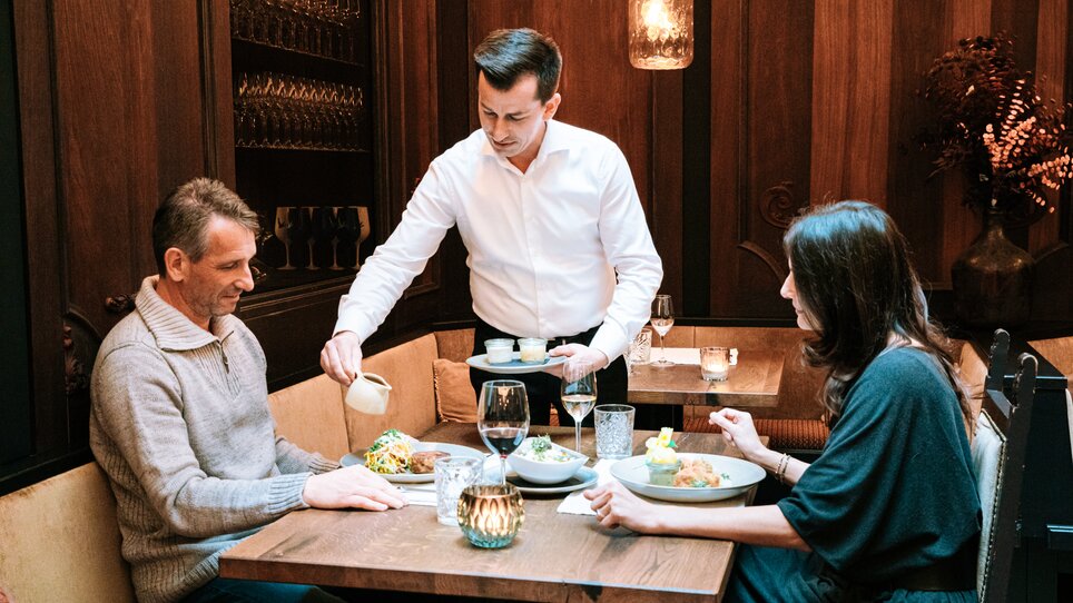 Zum Abendessen in Graz: Kellner serviert delikate Speisen an einem Tisch. | © Graz Tourismus