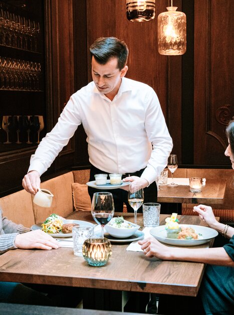 Dinner in Graz: Waiter serving delicious dishes at a table. | © Graz Tourismus
