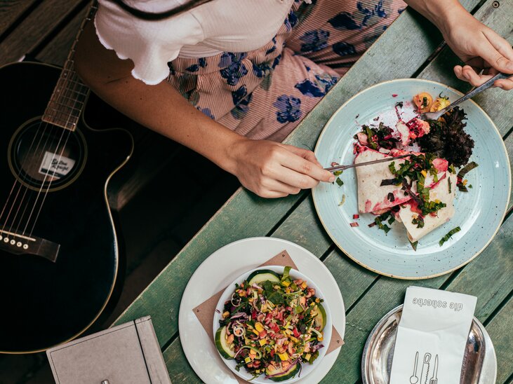 Eine Person isst ein leckeres Gericht in Graz, während eine Gitarre neben ihr liegt. | © Graz Tourismus