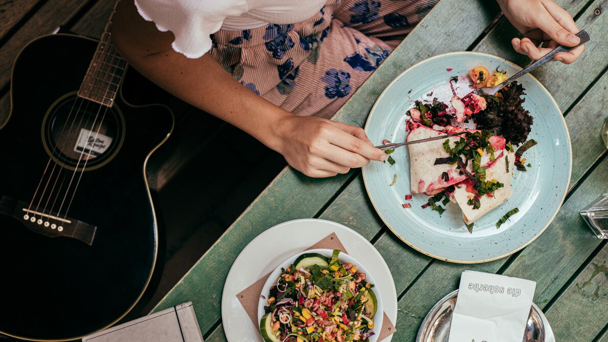A person enjoys a delicious dish in Graz, with a guitar beside them. | © Graz Tourismus