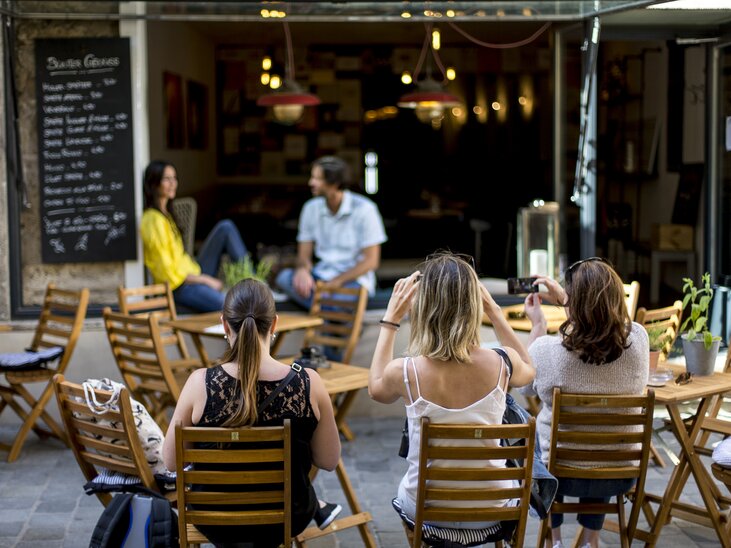 Gemütlicher Café-Bereich in Graz mit Menschen und Menü-Tafel. | © Tom Lamm
