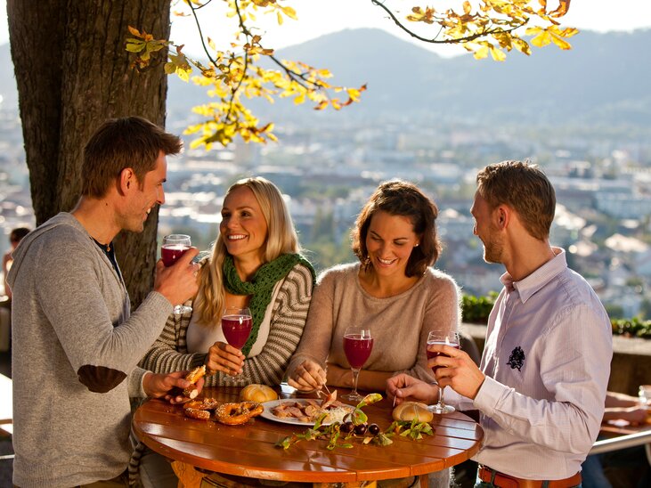 Freunde genießen Getränke und Snacks in Graz mit Blick auf die Stadt. | © Graz Tourismus - Tom Lamm