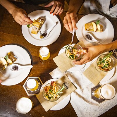 Verschiedene Gerichte und Biere auf einem Tisch beim Essen. | © Graz Tourismus - Werner Krug