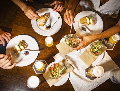 Verschiedene Gerichte und Biere auf einem Tisch beim Essen. | © Graz Tourismus - Werner Krug
