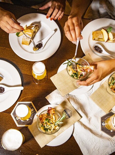 Verschiedene Gerichte und Biere auf einem Tisch beim Essen. | © Graz Tourismus - Werner Krug