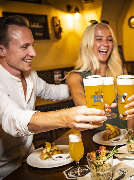 Freunde stoßen mit Bier an und genießen Essen in Graz. | © Graz Tourismus - Werner Krug