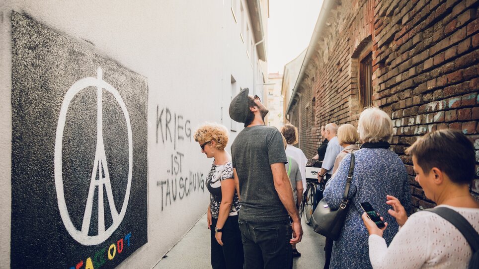 Eine Gruppe von Menschen in einer Gasse mit Graffiti in Graz. | © Graz Tourismus - Lupi Spuma