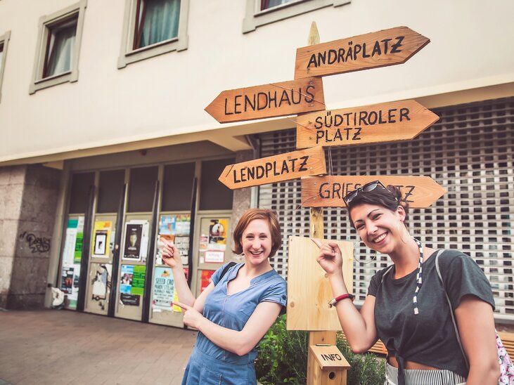 Zwei Frauen zeigen auf verschiedene Schilder in Graz, die Orte anzeigen. | © Graz Tourismus - Lupi Spuma