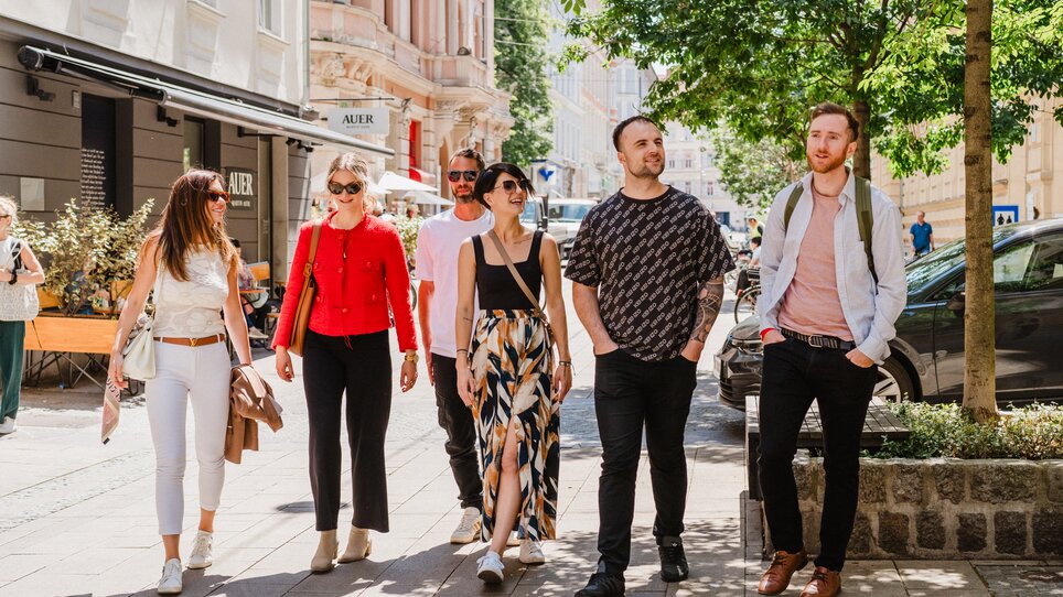Sechs Personen genießen einen sonnigen Tag in Graz bei einem geführten Stadtrundgang. | © 5komma5sinne - MotionAds