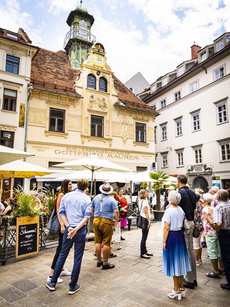 Group of visitors in front of the Glockenspiel at the Glockenspielplatz in Graz. | © Graz Tourismus - Werner Krug