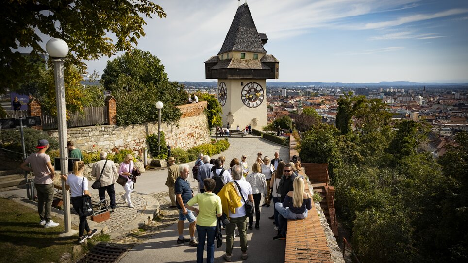 Der Grazer Uhrturm überblickt die Stadt Graz. Besucher genießen den Ausblick. | © Graz Tourismus - Werner Krug