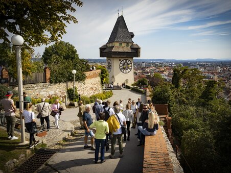 La Torre dell'Orologio di Graz sovrasta la città di Graz. I visitatori godono della vista. | © Graz Tourismus - Werner Krug