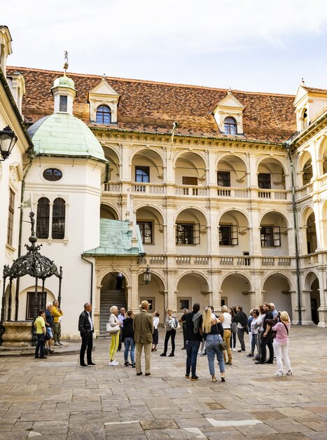 A group of tourists in the courtyard of a historic building in Graz, surrounded by columns and arches. | © Graz Tourismus - Werner Krug