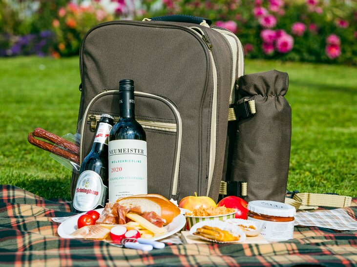 Ein Rucksack und Picknickessen im Park, umgeben von Blumen. | © Mias Photoart