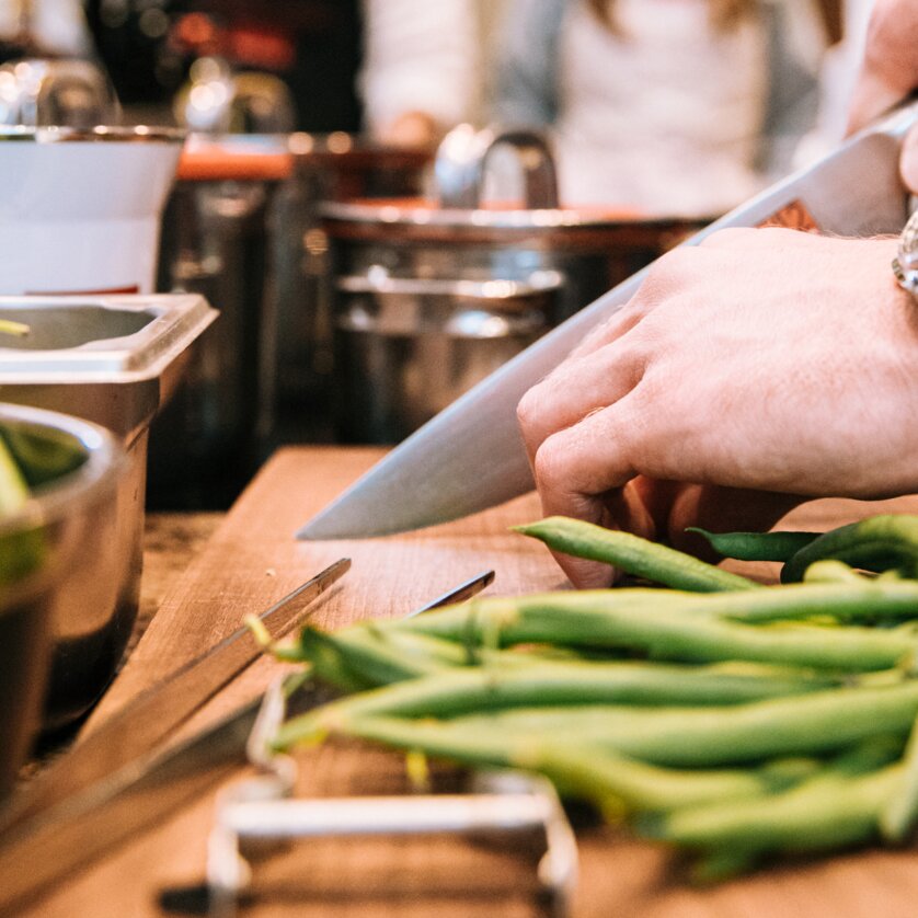 A chef is slicing green beans while others are working in the kitchen. | © Graz Tourismus