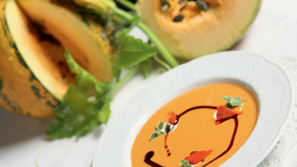 Feine Kürbissuppe in einem eleganten Teller, umgeben von Kürbis. | © Graz Tourismus - Harry Schiffer