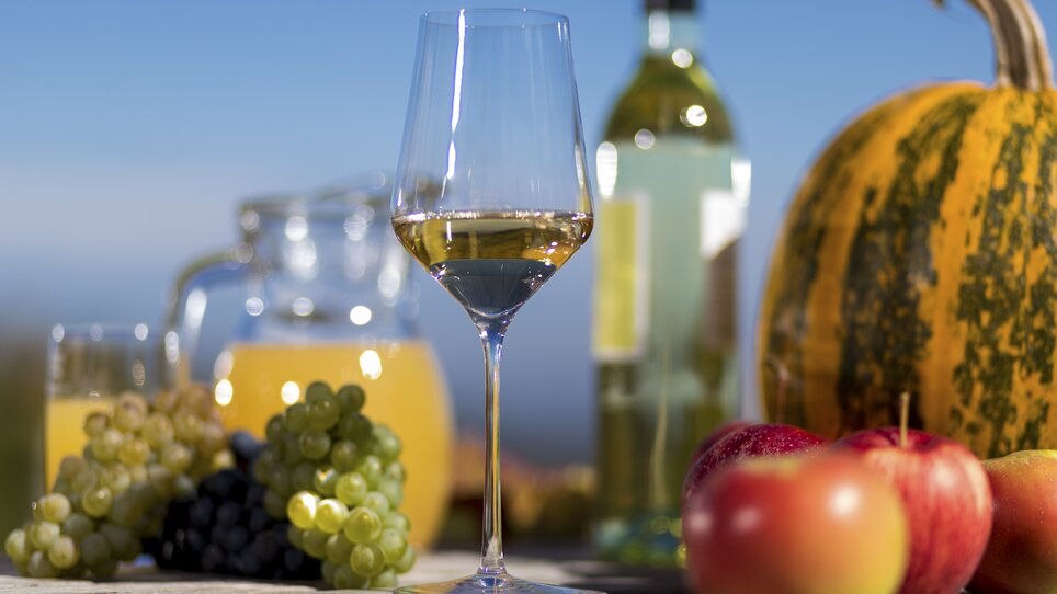 A glass of wine, grapes, apples, and a pumpkin in the autumn sun. | © Steiermark Tourismus - Harry Schiffer
