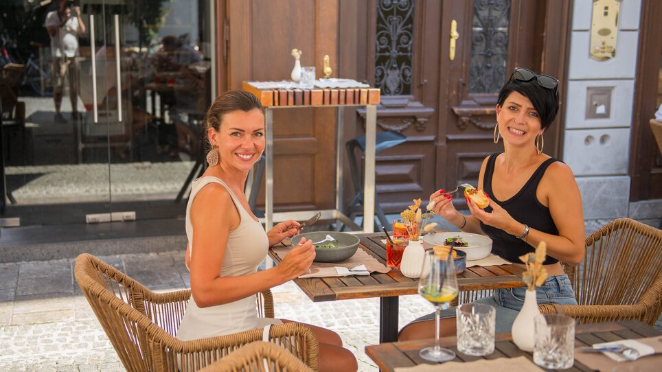 Two women enjoy their meal outdoors in the restaurant "dreizehn by Gauster" in Graz. | © 5komma5sinne - Helmut Schweighofer