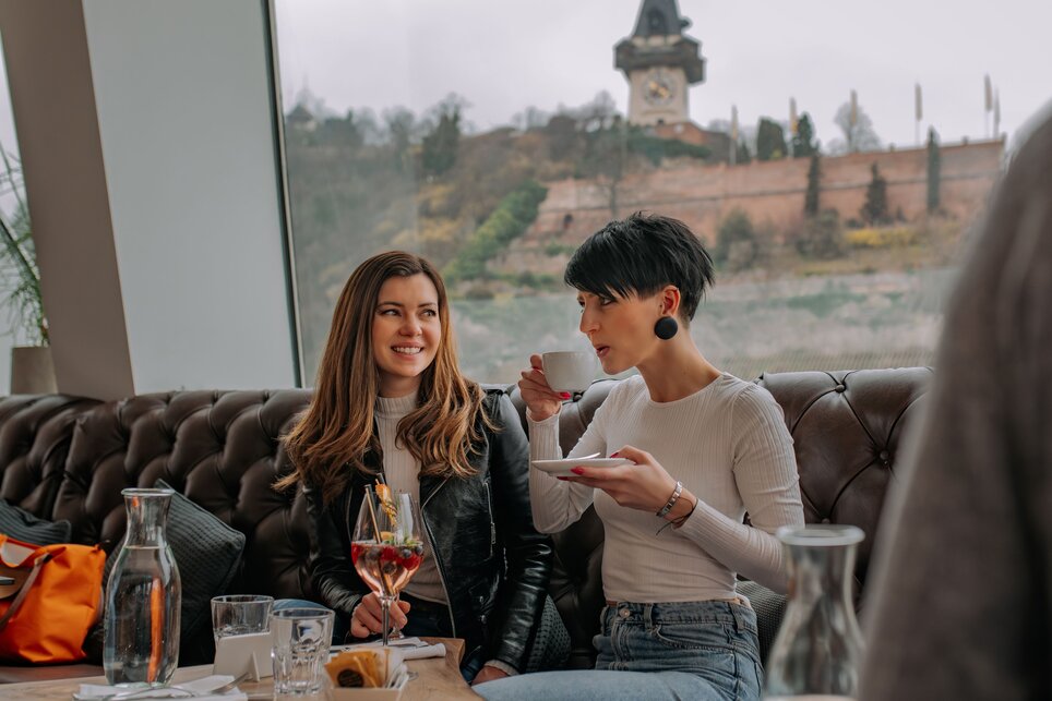 Due donne al Tagescafé Freiblick a Graz con il Torre dell'Orologio di Graz sullo sfondo. | © 5komma5sinne - Rene Strasser Fotografie 