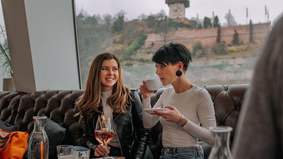 Zwei Frauen im Tagescafé Freiblick in Graz mit Graz Uhrturm im Hintergrund. | © 5komma5sinne - Rene Strasser Fotografie 
