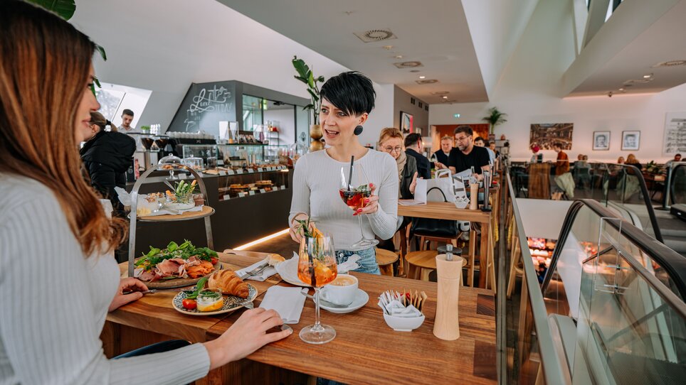 Two women at Tagescafé Freiblick in Graz enjoying drinks and food. | © 5komma5sinne - Rene Strasser Fotografie 