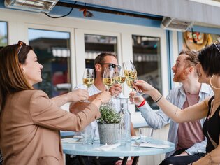 Friends cheers with glasses on a terrace in Graz. | © 5komma5sinne - MotionAds
