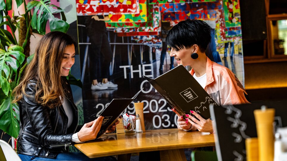 Zwei Frauen im Kunsthauscafé in Graz beim Lesen der Speisekarte. | © 5komma5sinne - Rene Strasser Fotografie 