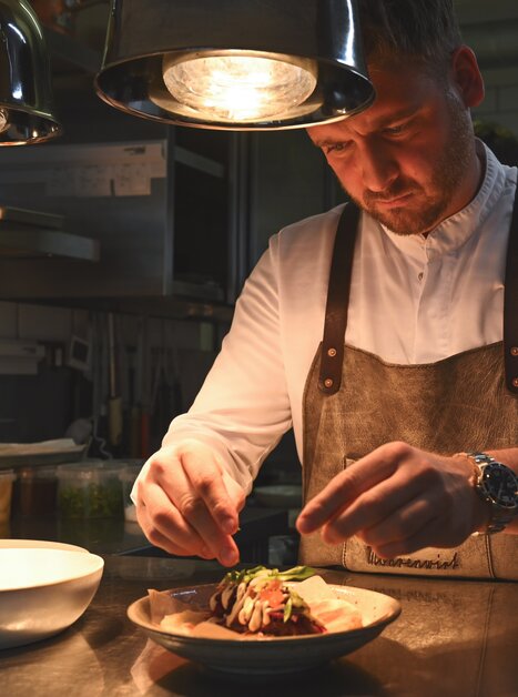 Un cuoco guarnisce un piatto al ristorante Mohrenwirt di Graz. | © 5komma5sinne - Rene Strasser Fotografie 