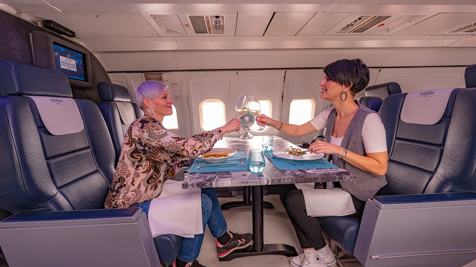 Two women clink glasses in an airplane. | © 5komma5sinne - Rene Strasser Fotografie
