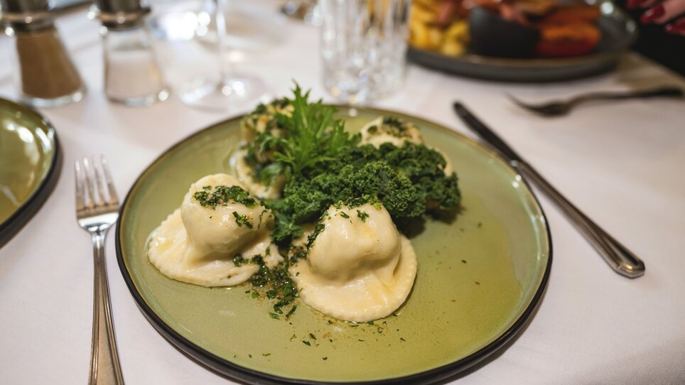 Gefüllte Teigtaschen mit Kräutern auf einem grünen Teller. | © 5komma5sinne - Rene Strasser Fotografie 