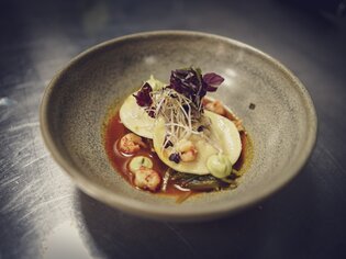 Ein kunstvoll angerichtetes Gericht mit Ravioli, Garnelen und grüner Sauce. | © ROLLING PIN