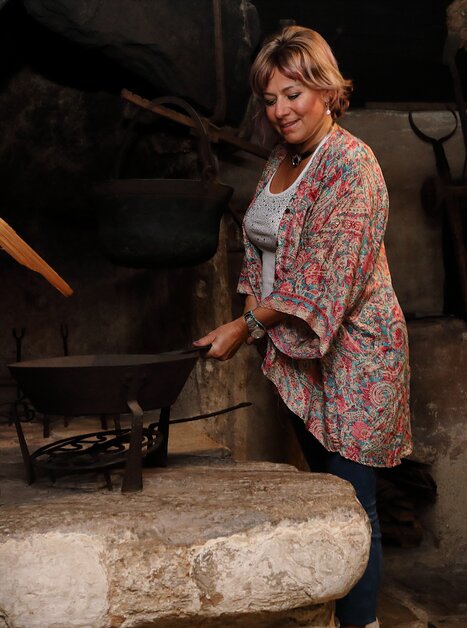 Frau steht an einem historischen Herd im Volkskundemuseum. | © Universalmuseum Joanneum - J. J. Kucek