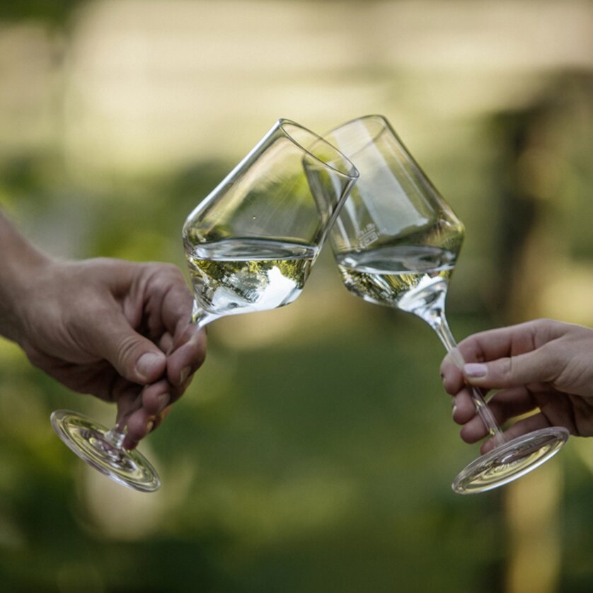 Two wine glasses with white wine clink together. | © Hubert Uranjek