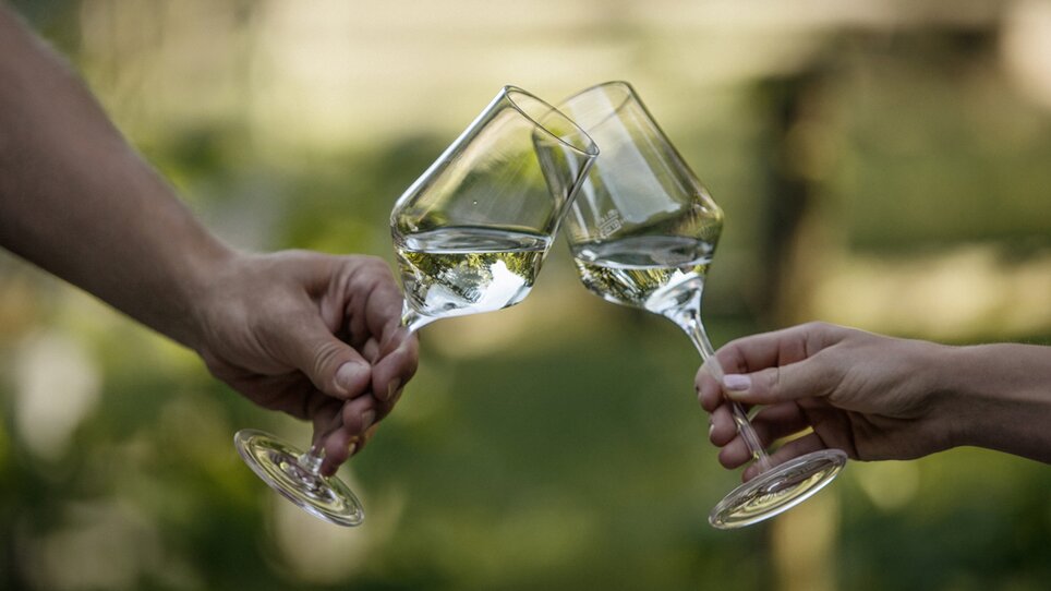 Zwei Hände mit Weingläsern mit Weißwein stoßen an. | © Hubert Uranjek