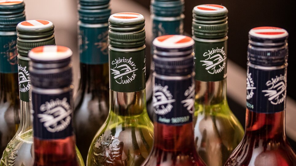 Bunte Flaschen "Steirischer Junker Wein" bei einer Präsentation. | © Fotokuchl